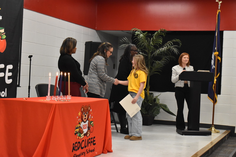 Student on stage shaking hands with staff.