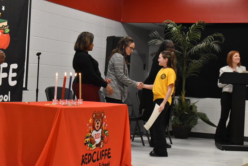 Student on stage shaking hands with staff.
