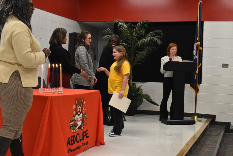 Student on stage shaking hands with staff.