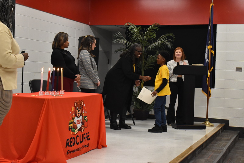 Student on stage shaking hands with staff.