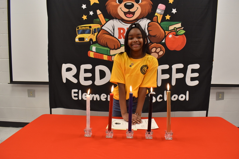 Student standing behind candles.