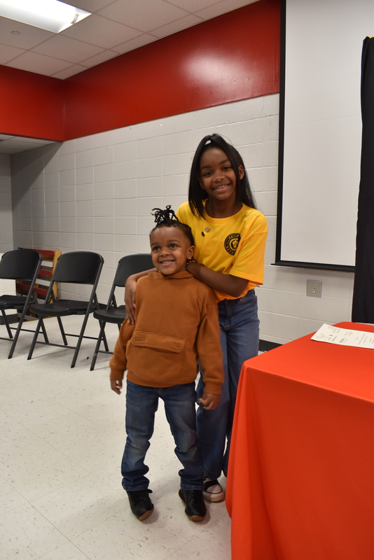 Student with small boy on stage.