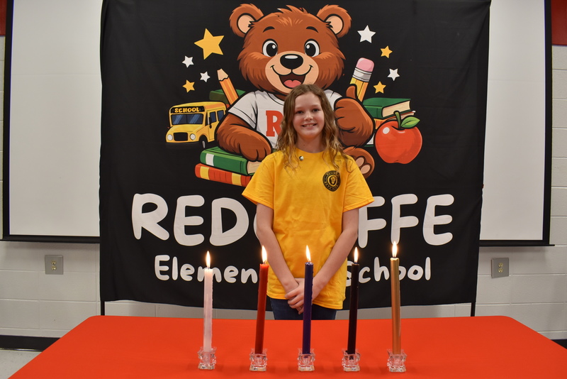 Student standing behind candles.