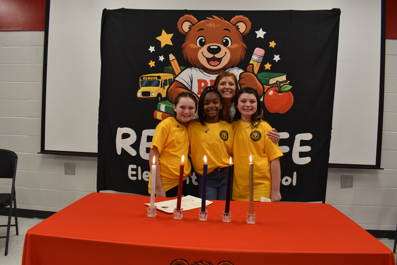 Three girls and woman standing behind candles.