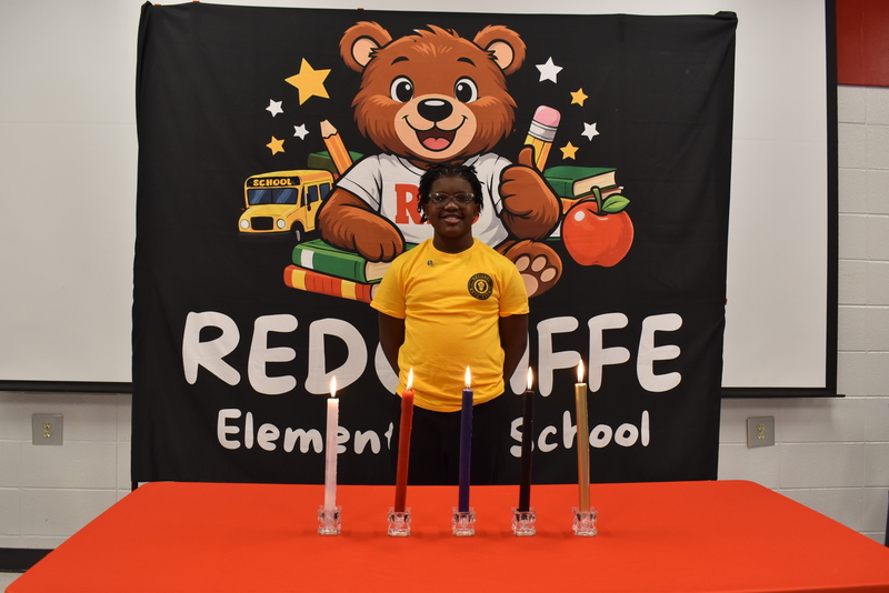 Student standing behind candles.