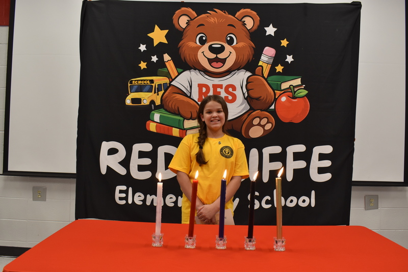 Student standing behind candles.