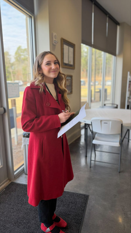 Student waiting to interview  other students while holding a pen and notebook. 