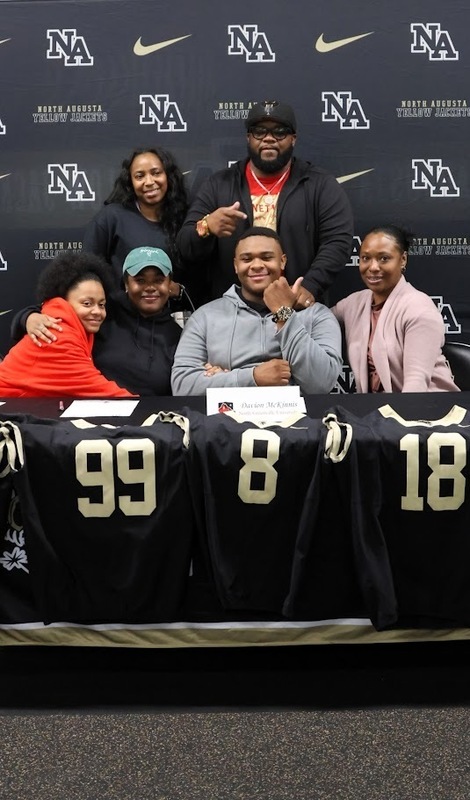 Football player surrounded by family.