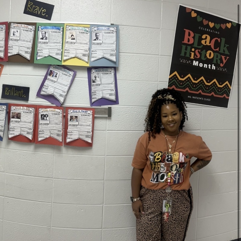Staff dressed in cultural attire with student work.