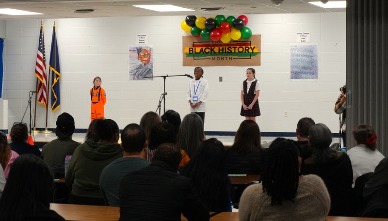 Four students participate in living wax museum during Black History Month Event. 