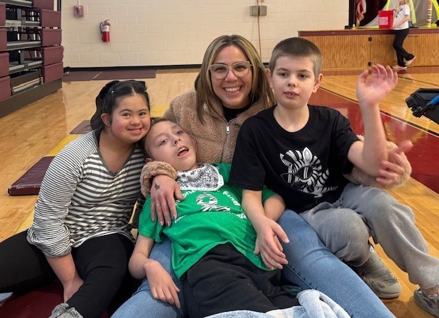 A teacher sits with three children.