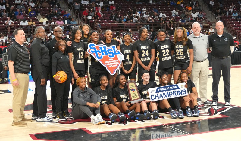 North Augusta Girls Basketball poses with trophy and signs.