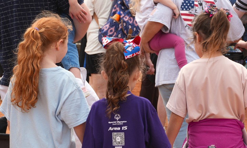 Three girls hold hands and walk away from the camera.