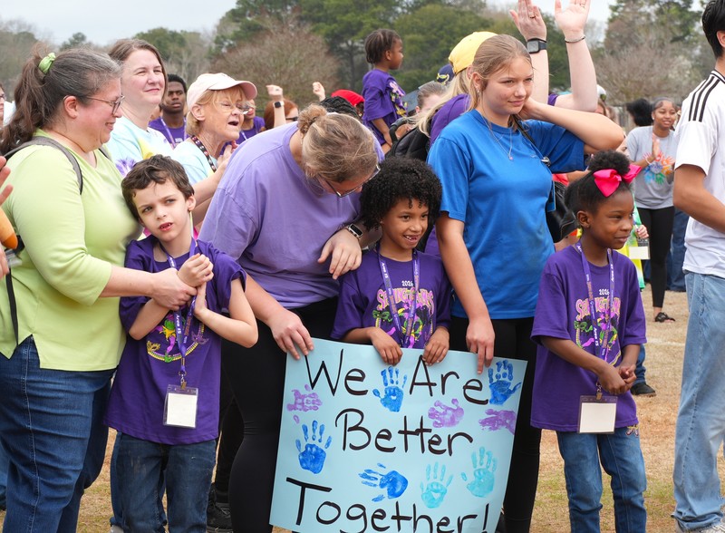 Aiken County students hug and hold a poster that reads 'We are Better Together'.