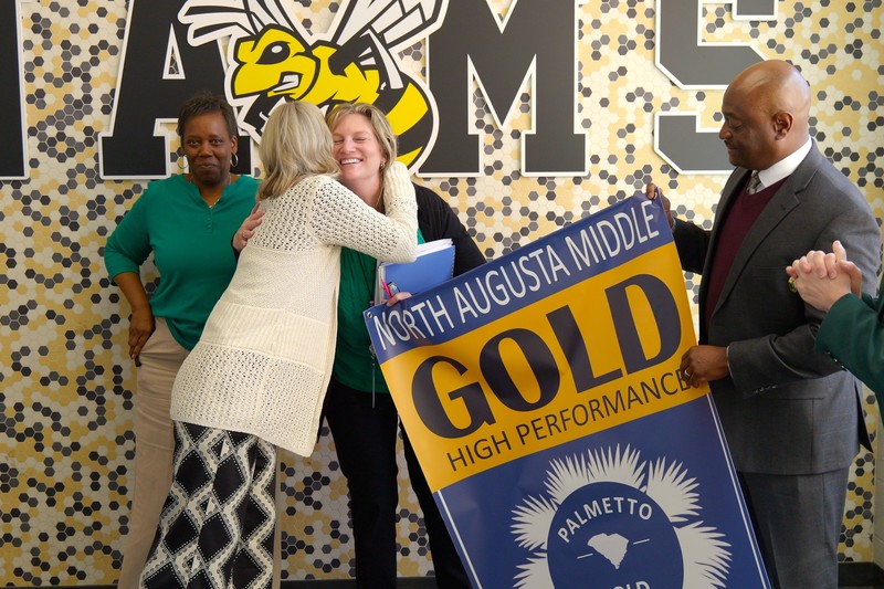 A hug happens while holding big performance banner.