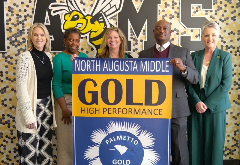 North Augusta Middle school stands with new Gold performance banner.