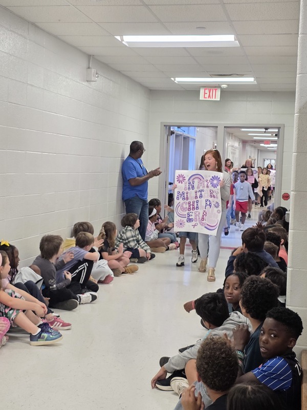 Students and staff walking through the hall in parade.