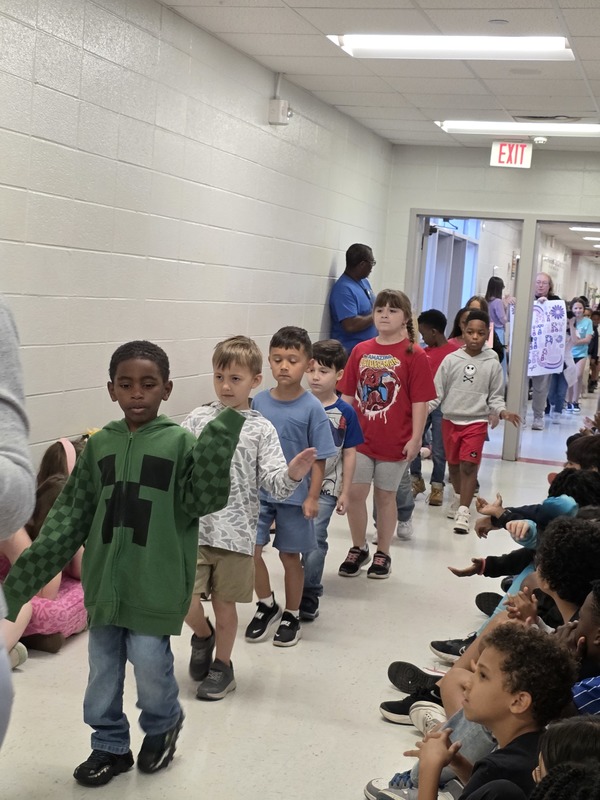 Students and staff walking through the hall in parade.