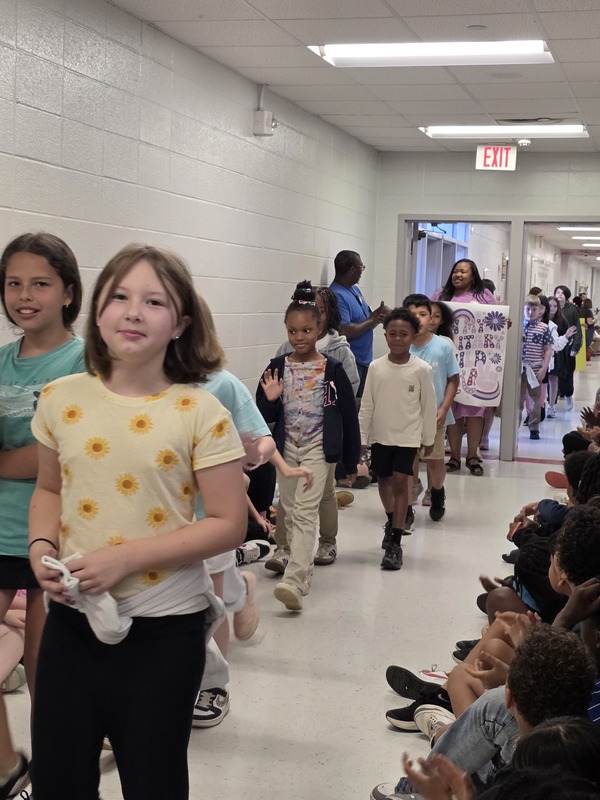 Students and staff walking through the hall in parade.