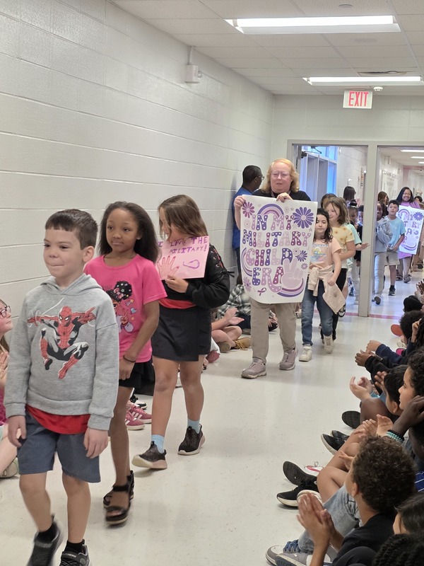 Students and staff walking through the hall in parade.