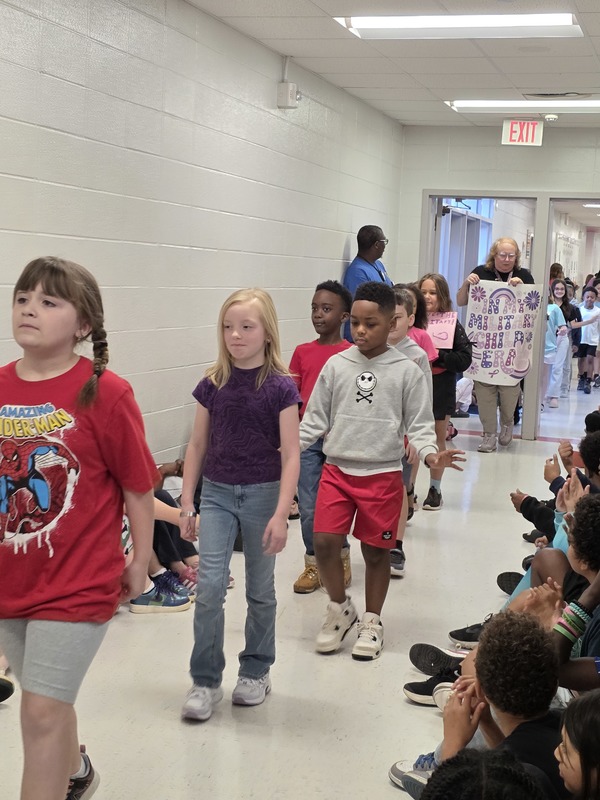 Students and staff walking through the hall in parade.