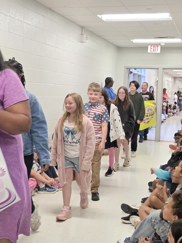 Students and staff walking through the hall in parade.