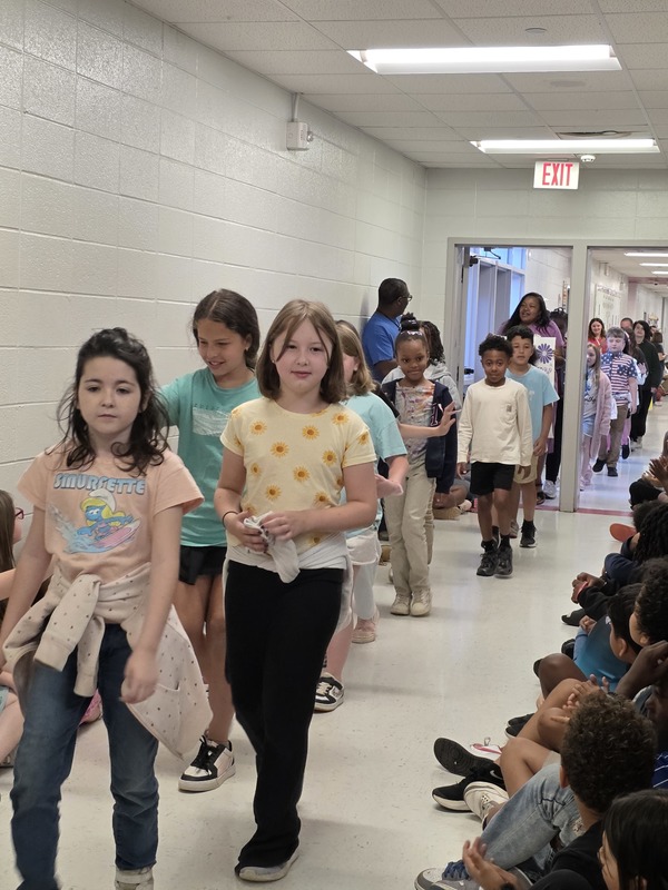 Students and staff walking through the hall in parade.