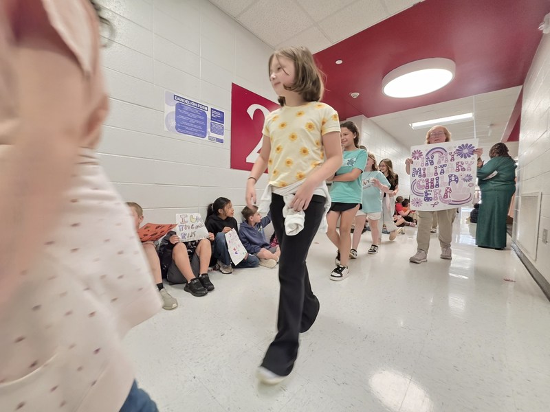 Students and staff walking through the hall in parade.