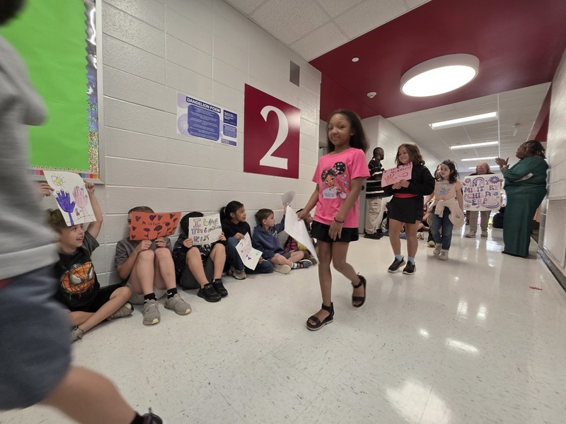 Students and staff walking through the hall in parade.