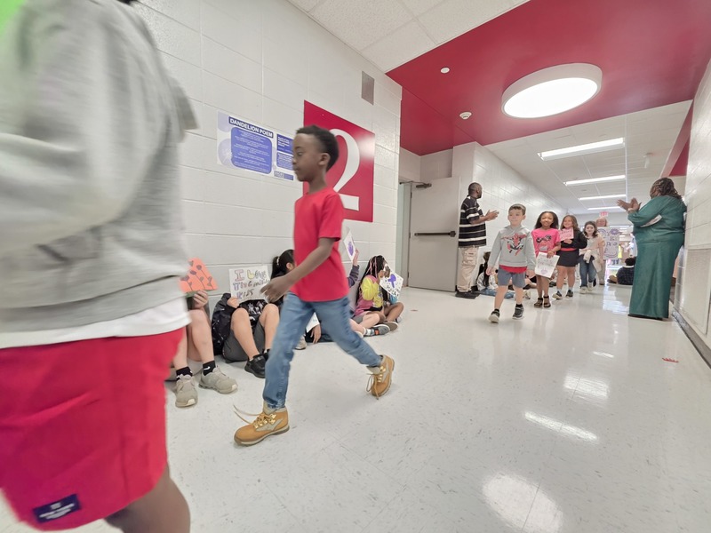 Students and staff walking through the hall in parade.