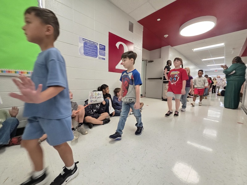 Students and staff walking through the hall in parade.