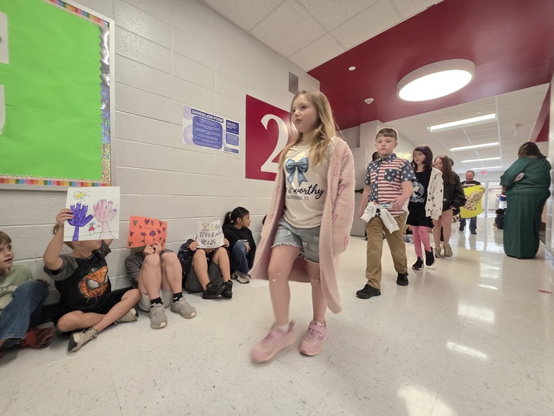 Students and staff walking through the hall in parade.