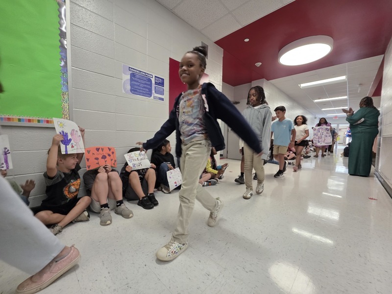 Students and staff walking through the hall in parade.