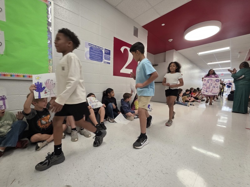Students and staff walking through the hall in parade.