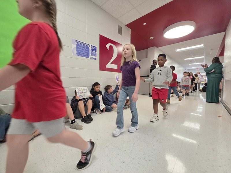 Students and staff walking through the hall in parade.