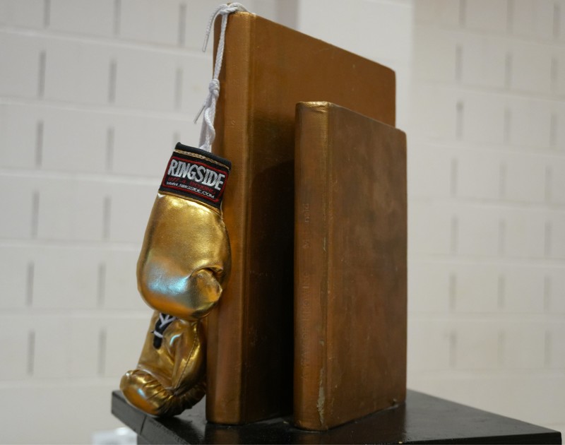 A close up view of the Elementary Battle of the Books featuring a golden set of boxing gloves and books.