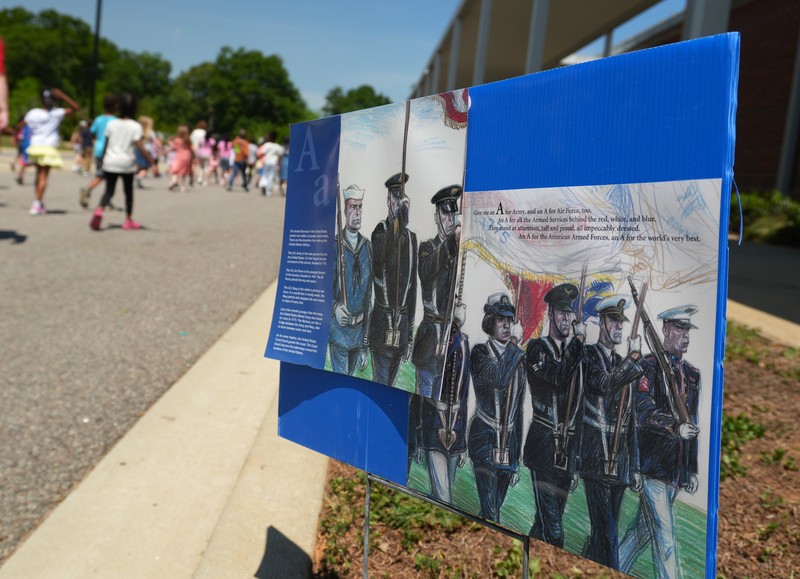 Posters about the military line the carloop where Millbrook students participate in a walk-a-thon.