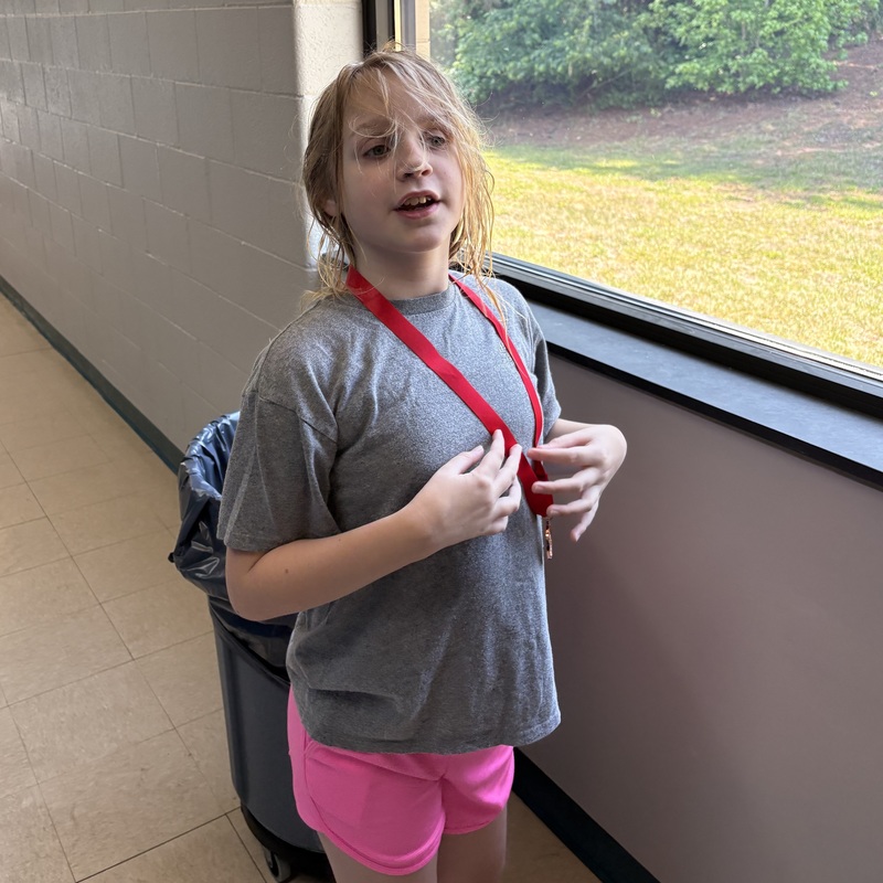 A female student stands with a medal around her neck.