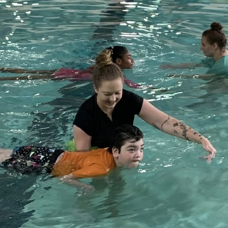 Two adults are with two children in a swimming pool.