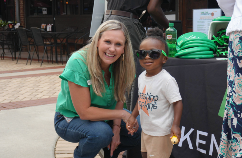 ACPSD employee smiling with young student at table.
