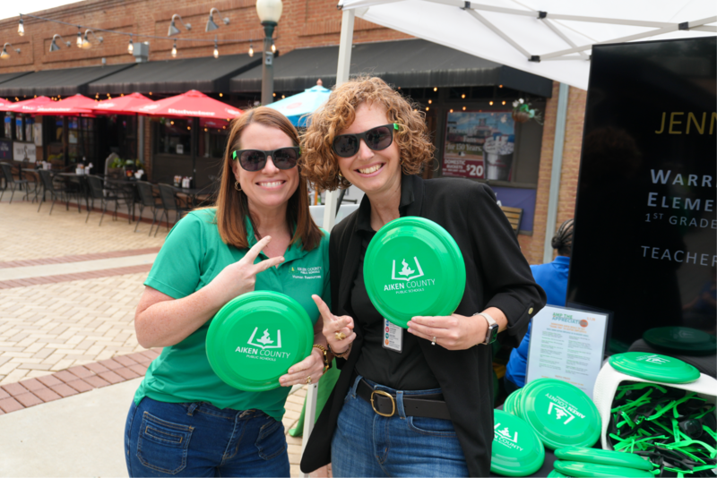 Two ACPSD employees holding ACPSD merch.