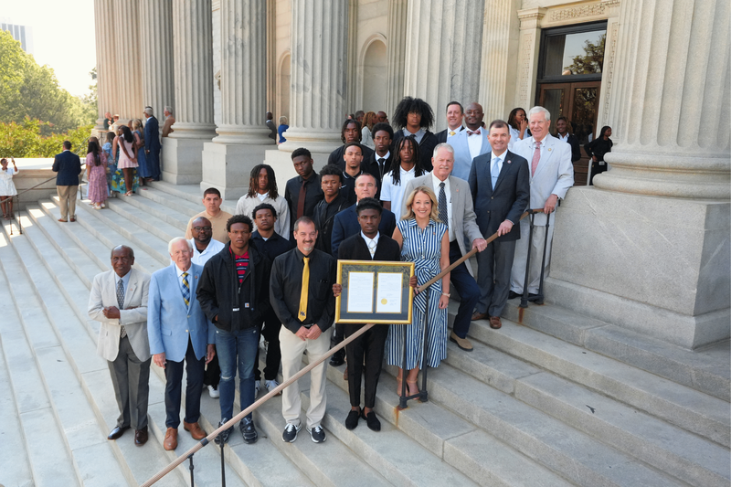 NAHS boys team posing on steps with the house resolution.