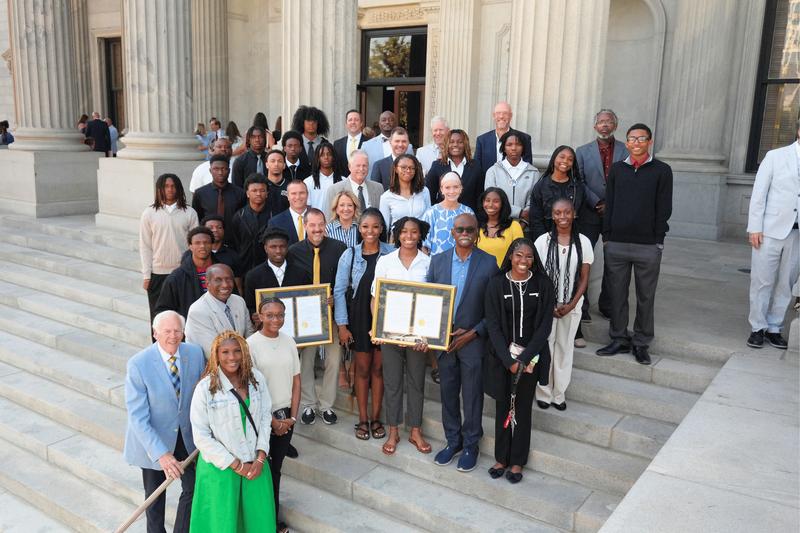 Both the boys' and girls' NAHS basketball teams holding the house resolutions on the steps of the state house.