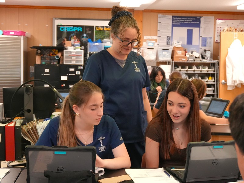 Dr. Christie Palladino assists two biomedicine students with a lab.