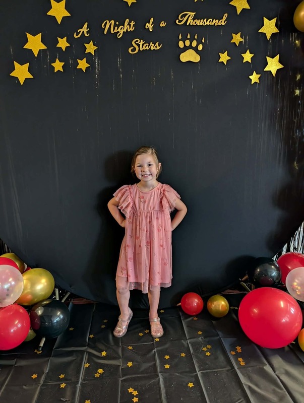 Student posing in front of black backdrop that says "Night of a Thousand Stars".