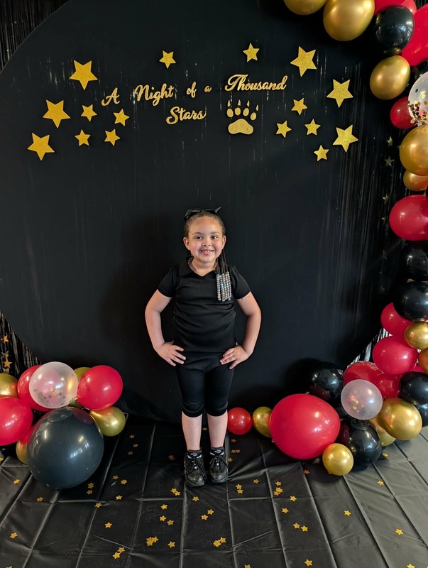 Student posing in front of black backdrop that says "Night of a Thousand Stars".