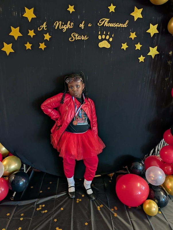 Student posing in front of black backdrop that says "Night of a Thousand Stars".