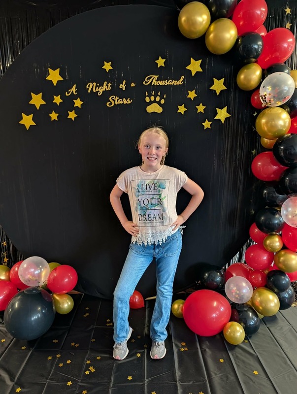 Student posing in front of black backdrop that says "Night of a Thousand Stars".