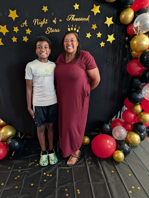 Student and staff posing in front of black backdrop that says "Night of a Thousand Stars".