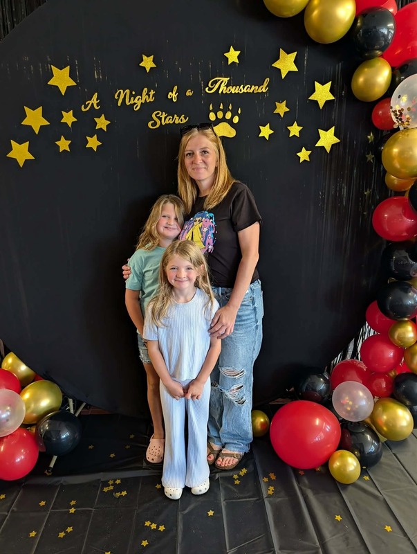 Family of three posing in front of black backdrop that says "Night of a Thousand Stars".